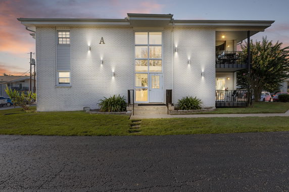 Front view of a two-story apartment building with a central entrance and illuminated exterior.