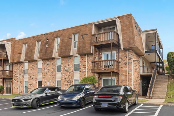 Front view of a multi-story building with balconies and parking area.