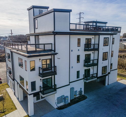 Front view of a multi-story building with large balconies and flat rooftops.