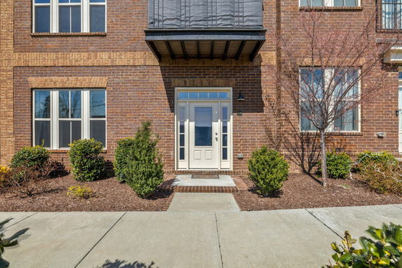 Front view of a brick building with multiple windows and a white door.