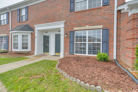 Front view of a two-story brick townhouse with white trim and multiple windows.