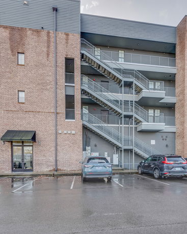 Exterior view of a building with visible staircases and parked cars.