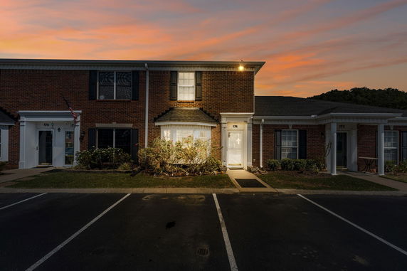 Front view of a brick two-story townhouse with parking area in front.