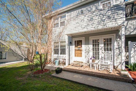 Front view of a two-story house with a porch and rocking chairs.