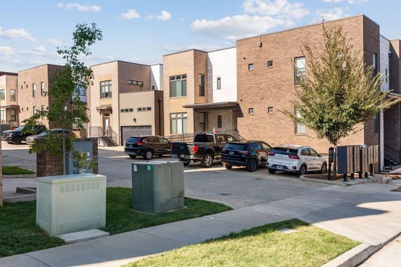 Front view of modern townhouses with parking area.