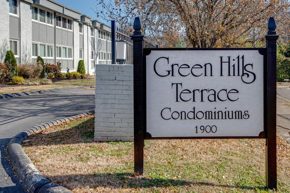 Front view of a multi-story condominium building with a sign that reads 'Green Hills Terrace Condominiums 1900'.
