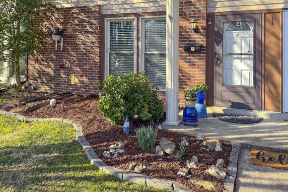 Front view of a house entry with a brick exterior and a garden bed.