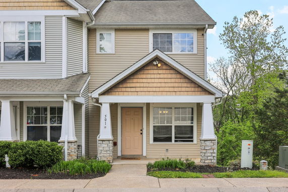 Front view of a two-story house with beige siding and stone accents.