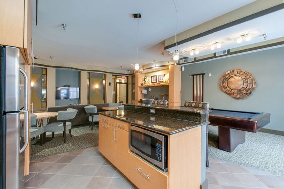 Interior of a room with a pool table, seating area, and kitchenette.