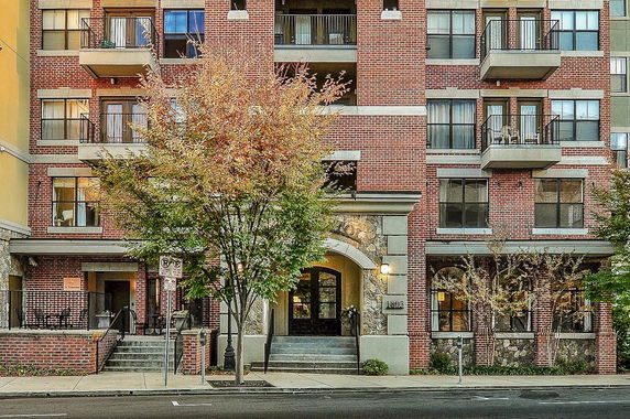 Front view of a multi-story brick apartment building with balconies.
