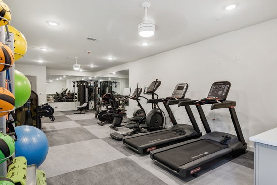 Indoor gym area with exercise equipment including treadmills and weights.
