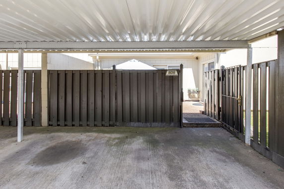 Covered parking area with simple gate and fence.