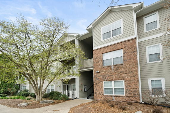 Front view of a multi-story apartment building with a mix of brick and siding exterior.