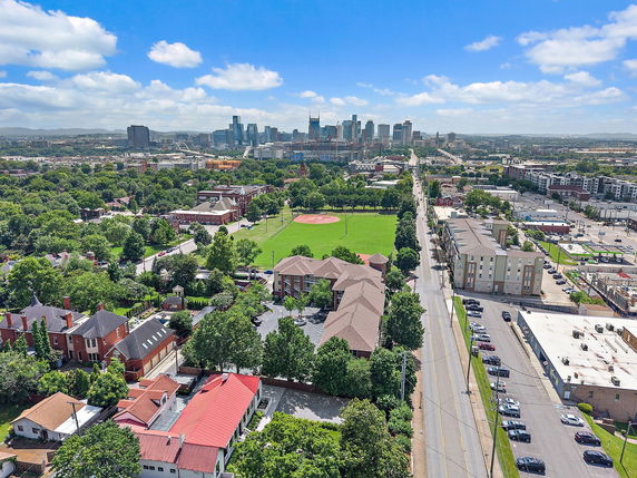 Aerial view over a residential and urban area with a city skyline in the distance.