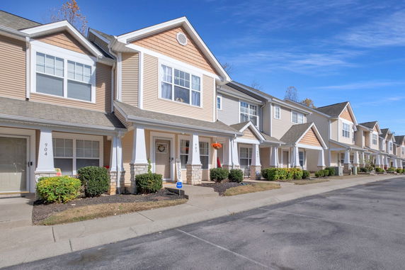 Front view of a row of townhouses with multiple stories and columns at the entrances.