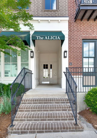 Front view of a building entrance with brick steps and a green awning labeled 'The ALICIA'.