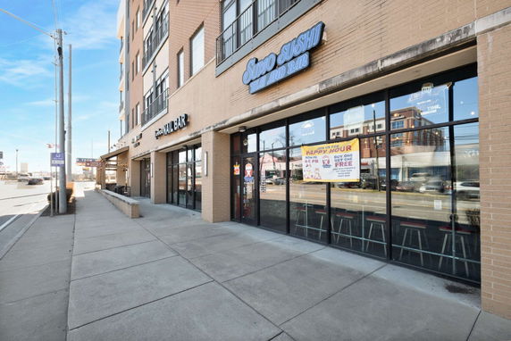 Front view of a commercial building with various shops, including a sushi bar and nail bar.