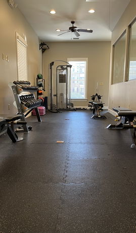 Room with gym equipment including weights and exercise machines.