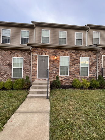 Front view of a two-story townhouse with brick and siding exterior.