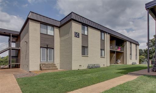 Front view of a two-story apartment building with an outdoor staircase and a covered entrance.