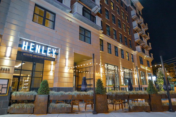 Front view of a multi-story building with restaurant signage and outdoor seating area.