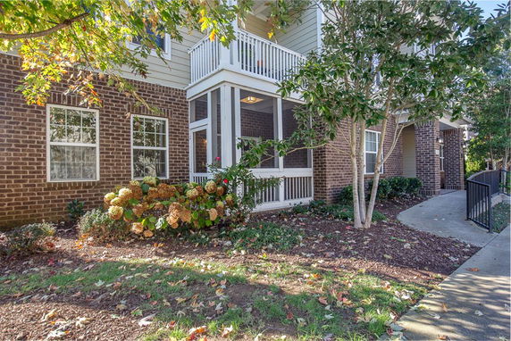 Front view of a house with a screened porch and brick facade.