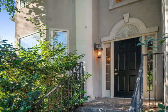 Front view of a house with a black door and decorative arch above the entrance.