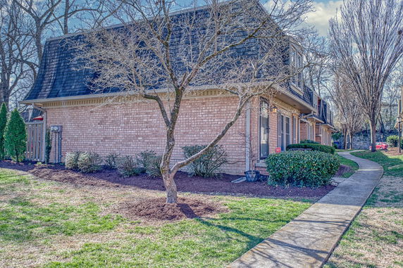 Front view of a brick two-story townhouse with a unique sloped roof.