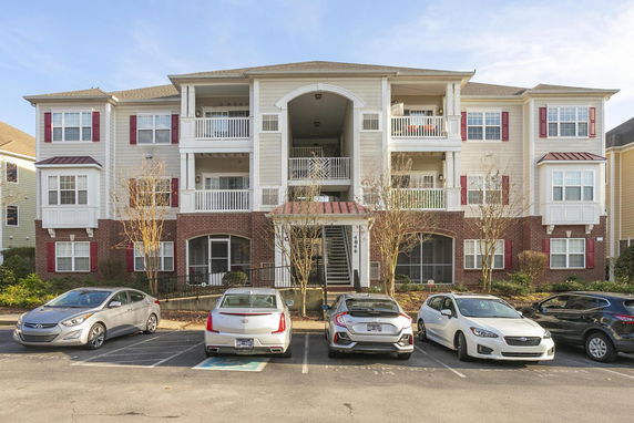 Front view of a multi-story apartment building with parking in front.