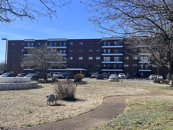 Front view of a multi-story residential building with balconies and parking area.