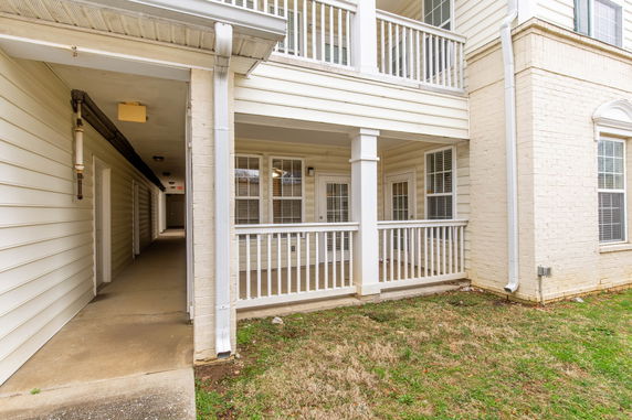 Front view of a multi-story house with balconies and a covered walkway.