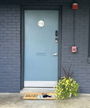 Front view of a building entrance with a blue door and decorative mat.