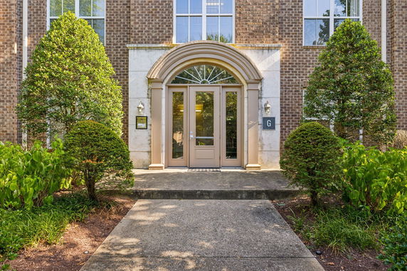 Front view of a building entrance with a brick facade and arched doorway.