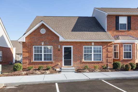 Front view of a single-story brick house with a gabled roof and large windows.