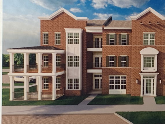 Front view of a multi-story brick building with balconies and multiple windows.