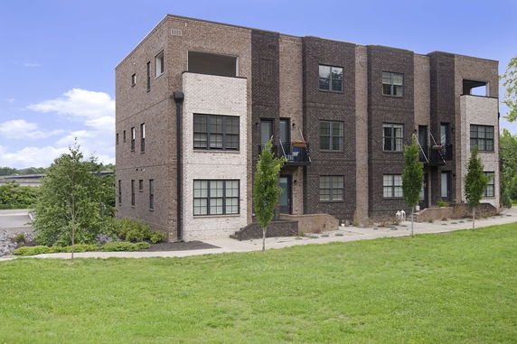 Front view of a three-story brick residential building with multiple balconies.