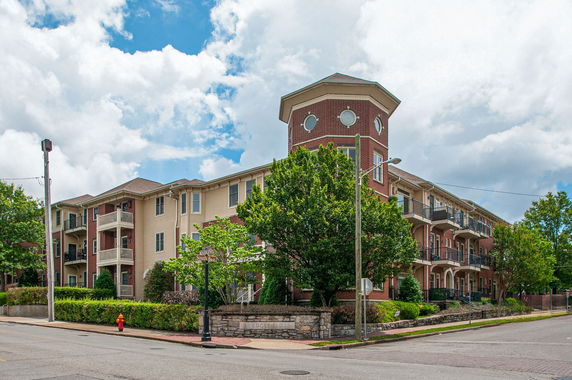 Front view of a multi-story building with a corner tower and balconies.