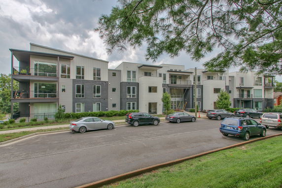 Front view of a modern multi-story apartment building with large windows and balconies.