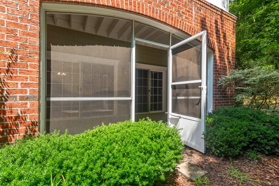 Front view of a house with a brick exterior and a screen door entrance.