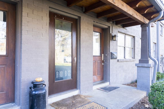 Front view of a building entrance with two wooden doors in a brick wall.