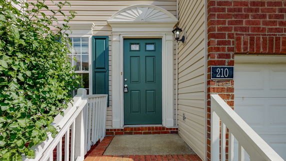 Front view of a house entrance with a green door and white railing.