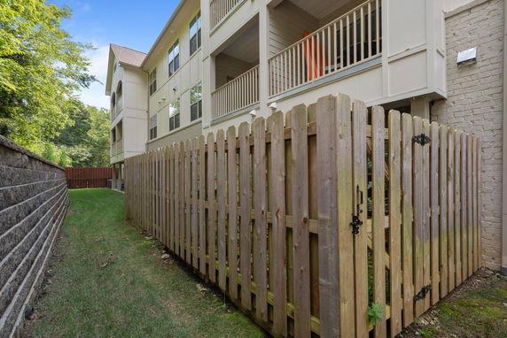 Side view of a multi-story building with fenced-in area.