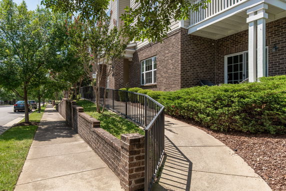 Front view of a brick building with a metal railing ramp and surrounding greenery.