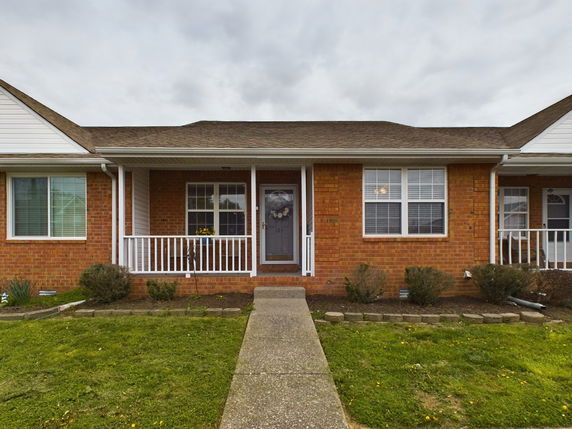 Front view of a single-story brick house with a porch and railing.