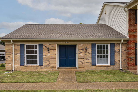Front view of a single-story house with a brick facade and blue shutters.