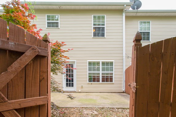 Rear view of a two-story house with beige siding and multiple windows.