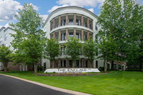 Front view of a multi-story building with balconies and brick pillars.