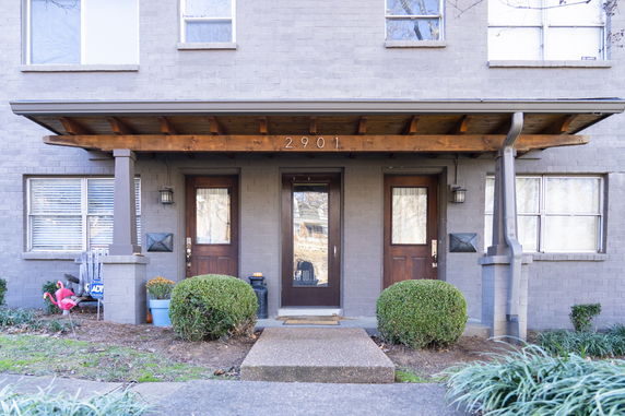 Front view of a two-story building entrance with two wooden doors and a covered walkway.