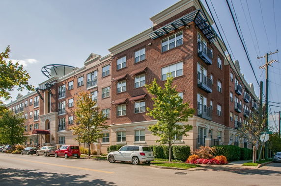 Front view of a multi-story brick apartment building on a street corner.