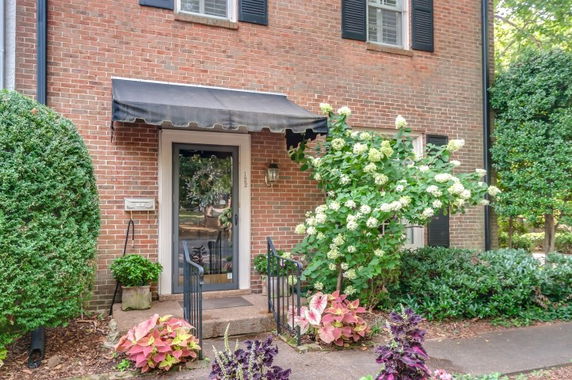Front view of a brick house with a black awning over the entrance.